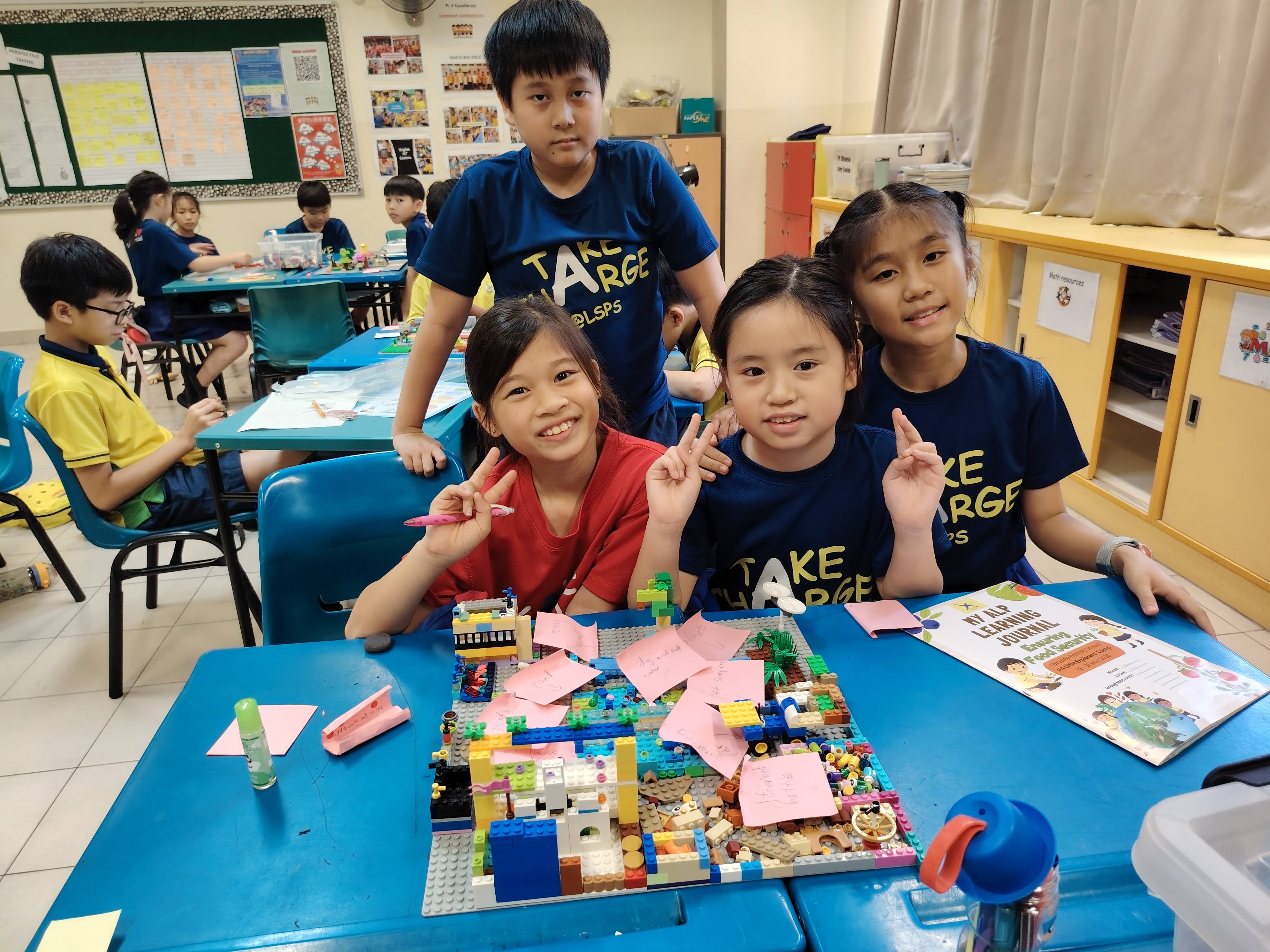 A group of four students pose for the camera with their completed lego prototype